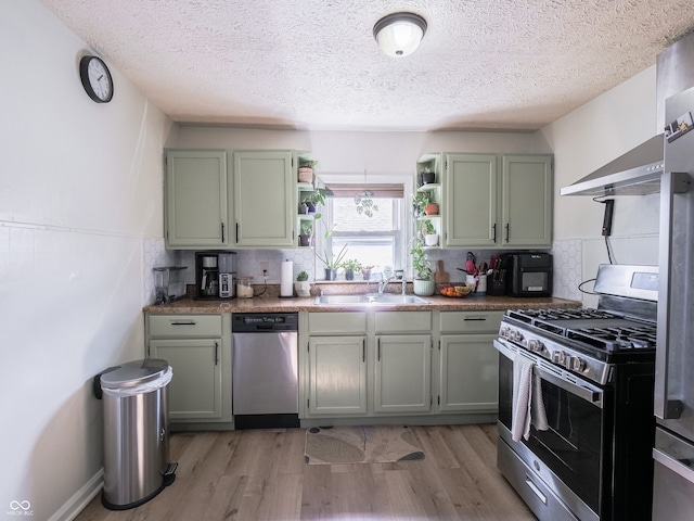 kitchen featuring stainless steel appliances, a sink, green cabinets, and open shelves