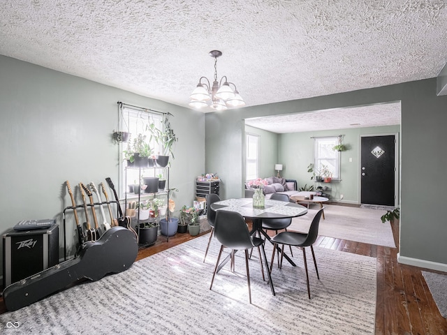 dining room featuring hardwood / wood-style flooring, a notable chandelier, baseboards, and a wealth of natural light