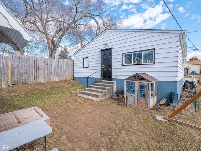 view of front of house featuring entry steps, a front yard, and fence