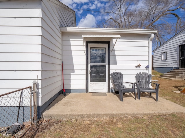 view of exterior entry with a patio and fence