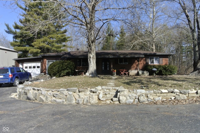 ranch-style home featuring a garage, brick siding, and aphalt driveway