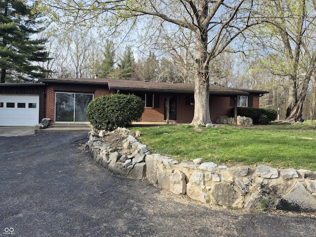 view of front of property featuring brick siding, a front lawn, an attached garage, and driveway