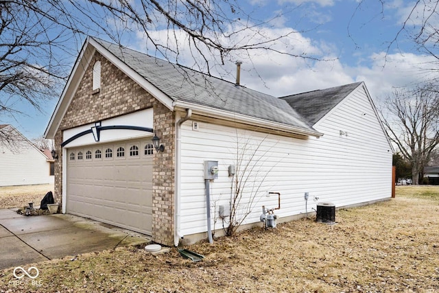 view of side of home featuring a garage, central AC, a shingled roof, and an outdoor structure