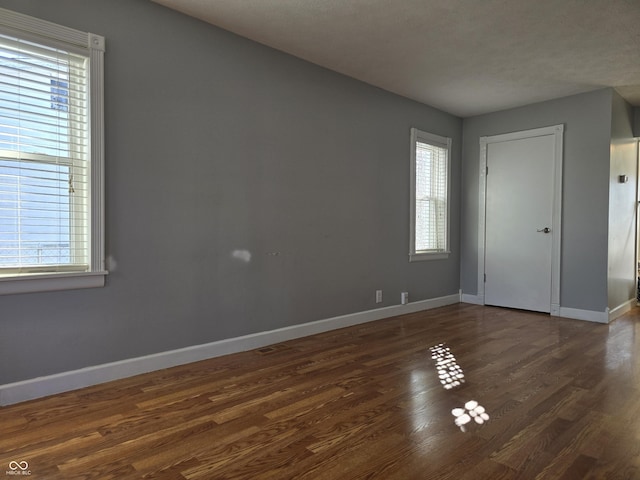 interior space featuring plenty of natural light, baseboards, and dark wood finished floors