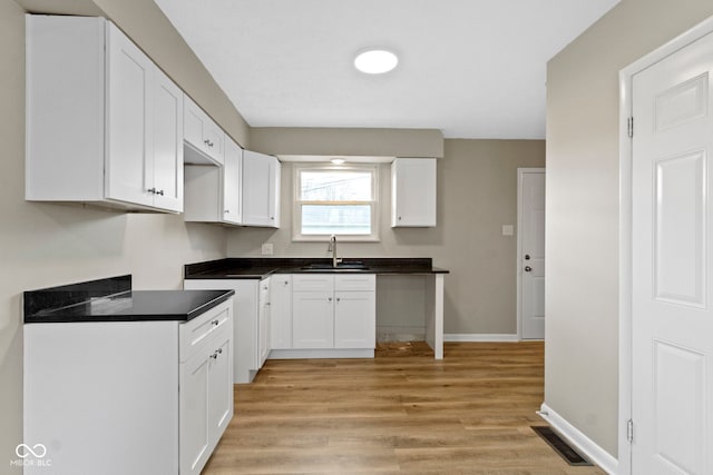 305 Bixler Rd, Indianapolis, IN 46227 - kitchen with visible vents, light wood-style floors, white cabinets, a sink, and baseboards