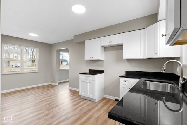 305 Bixler Rd, Indianapolis, IN 46227 - kitchen featuring light wood finished floors, baseboards, arched walkways, white cabinets, and a sink