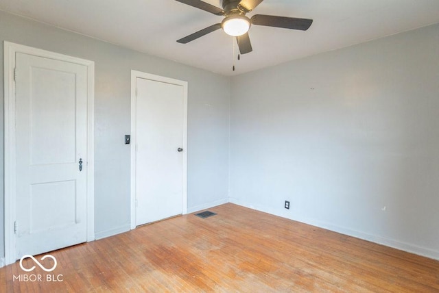 unfurnished bedroom featuring ceiling fan, wood finished floors, visible vents, and baseboards