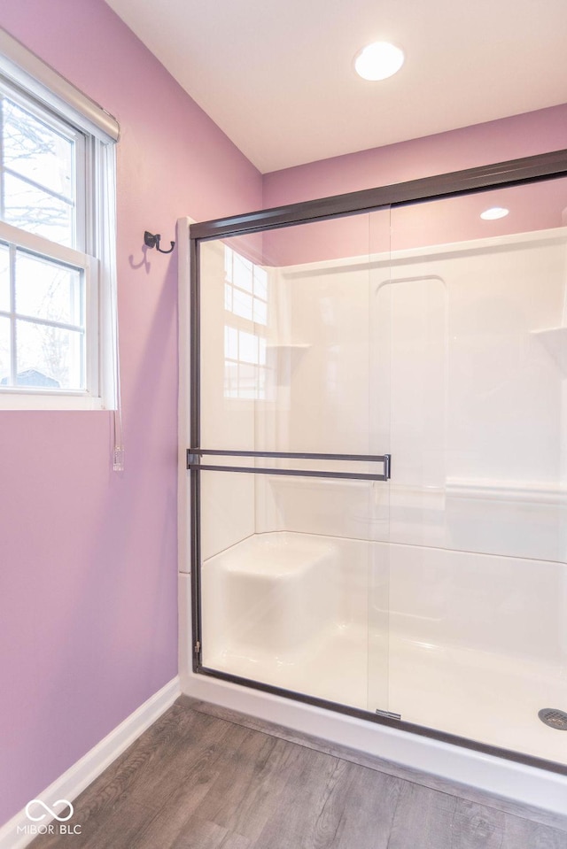 full bathroom with a stall shower, baseboards, and wood finished floors