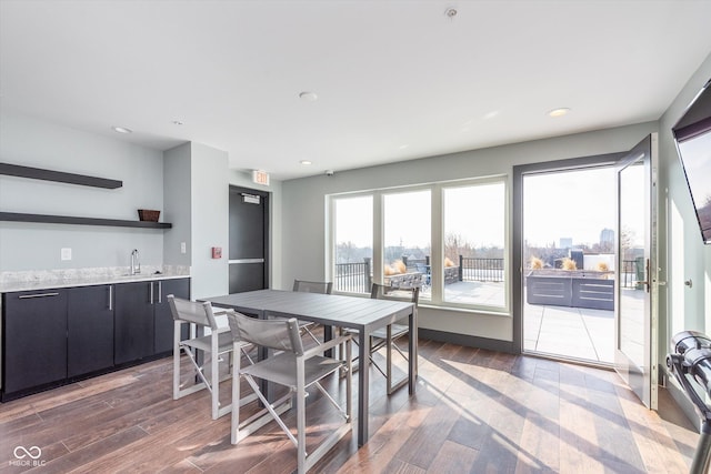 dining space with wet bar, wood finished floors, and recessed lighting