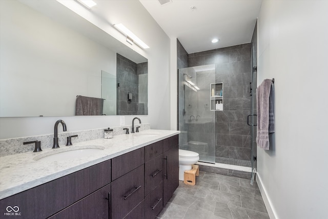 bathroom featuring double vanity, a stall shower, a sink, and toilet