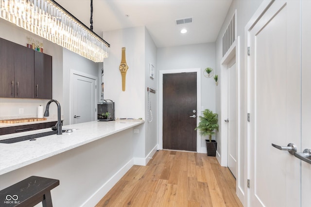 interior space featuring baseboards, visible vents, light wood-style floors, a sink, and recessed lighting