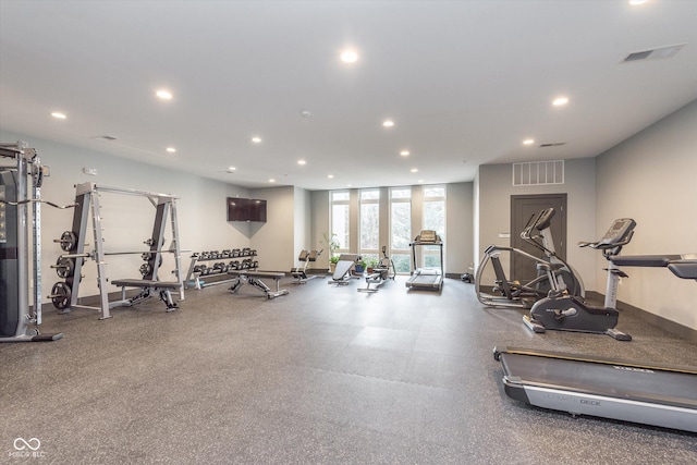 workout area with baseboards, visible vents, a wall of windows, and recessed lighting