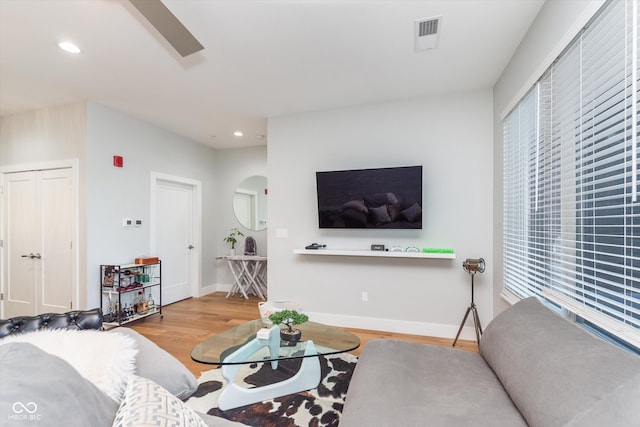 living area featuring a wealth of natural light, arched walkways, recessed lighting, and wood finished floors