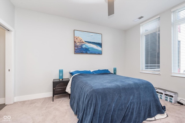 bedroom with light carpet, a ceiling fan, visible vents, and baseboards