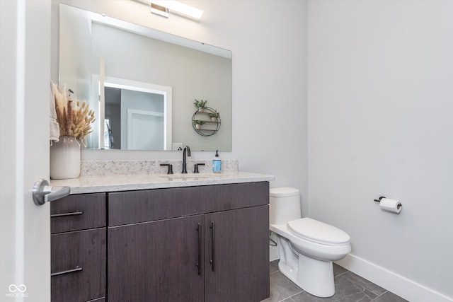 bathroom featuring toilet, tile patterned flooring, baseboards, and vanity