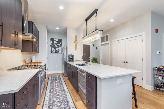 kitchen with stainless steel gas stove, light wood-style flooring, dark brown cabinets, a kitchen bar, and a sink