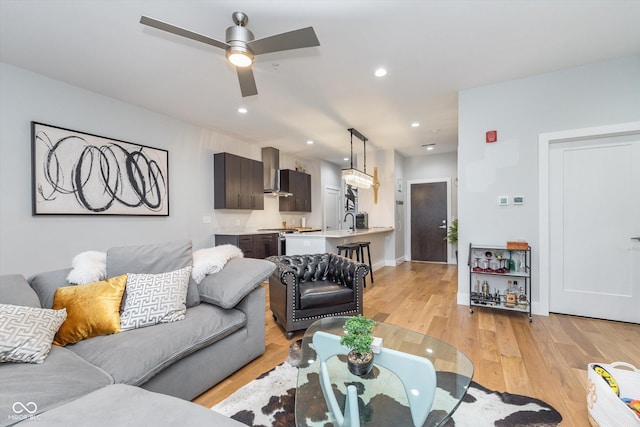 living room featuring light wood-style flooring, baseboards, a ceiling fan, and recessed lighting