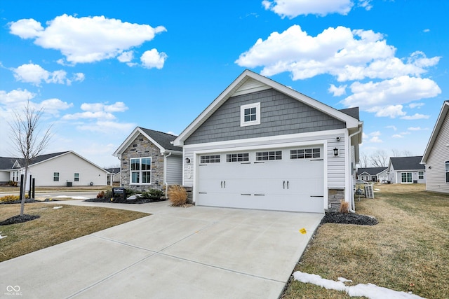 view of front of home featuring a garage, a front yard, stone siding, and driveway