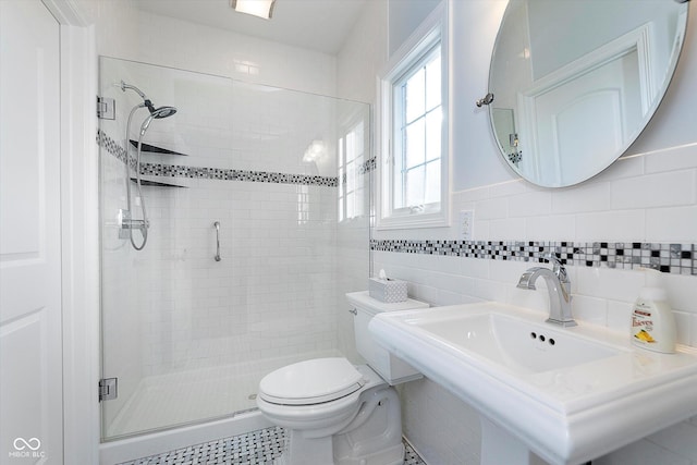 full bathroom with tile walls, a sink, toilet, and a shower stall