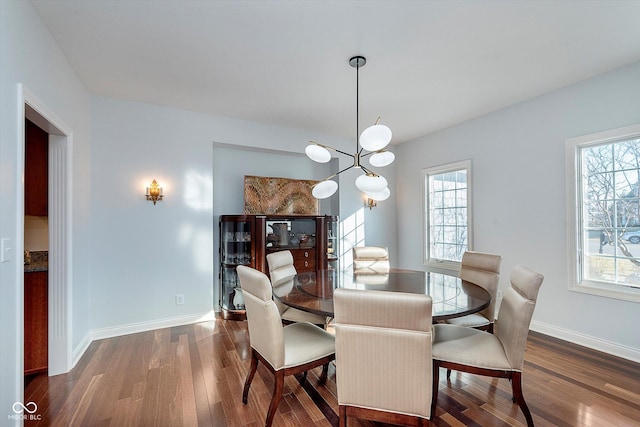 dining room featuring a notable chandelier, wood finished floors, and baseboards