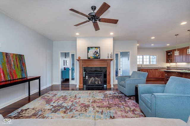 living area featuring a fireplace, recessed lighting, dark wood-type flooring, a ceiling fan, and baseboards