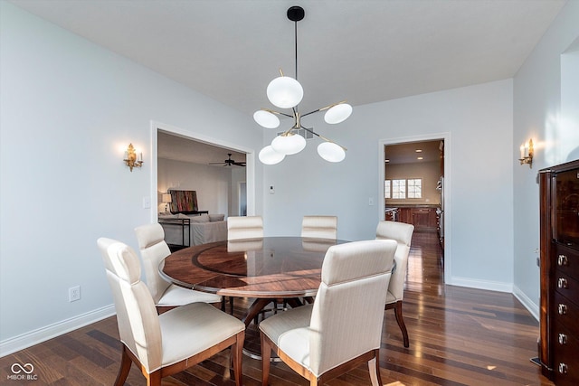 dining area with dark wood-type flooring, baseboards, and ceiling fan with notable chandelier