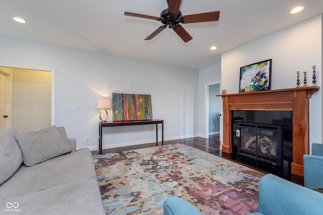 living room featuring recessed lighting, wood finished floors, a ceiling fan, baseboards, and a glass covered fireplace