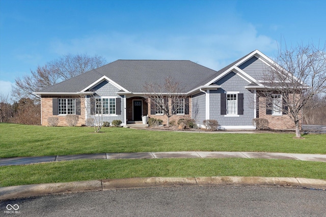 view of front of property featuring a shingled roof, a front lawn, and brick siding