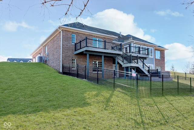 rear view of property with a wooden deck, stairs, a lawn, and brick siding