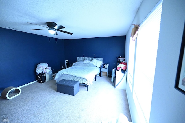 bedroom featuring a textured ceiling, carpet floors, visible vents, and a ceiling fan