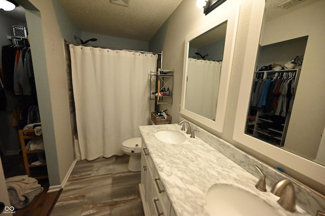 bathroom featuring double vanity, a sink, a textured ceiling, and wood finished floors