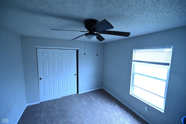 unfurnished bedroom with a textured ceiling, carpet floors, a closet, and baseboards