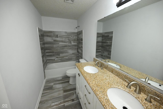 bathroom featuring toilet, a textured ceiling, and a sink