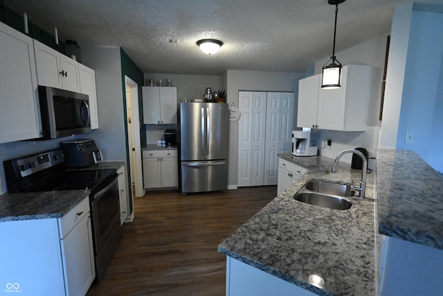 kitchen with stone countertops, stainless steel appliances, a sink, white cabinets, and dark wood finished floors