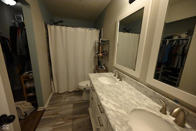 bathroom with double vanity, a sink, toilet, and wood finished floors