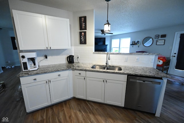 kitchen featuring white cabinets, a peninsula, stainless steel dishwasher, stone counters, and a sink