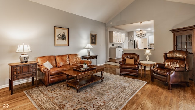 living area with vaulted ceiling, baseboards, wood finished floors, and a notable chandelier