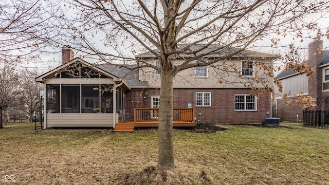 back of property with brick siding, a chimney, a lawn, a sunroom, and fence