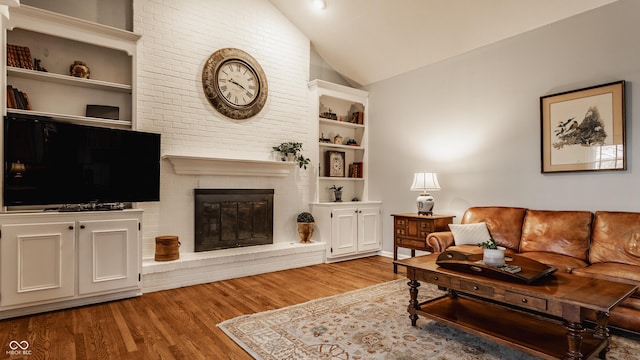 living room featuring lofted ceiling, a fireplace, and wood finished floors