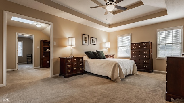 bedroom featuring baseboards, multiple windows, a tray ceiling, and carpet flooring