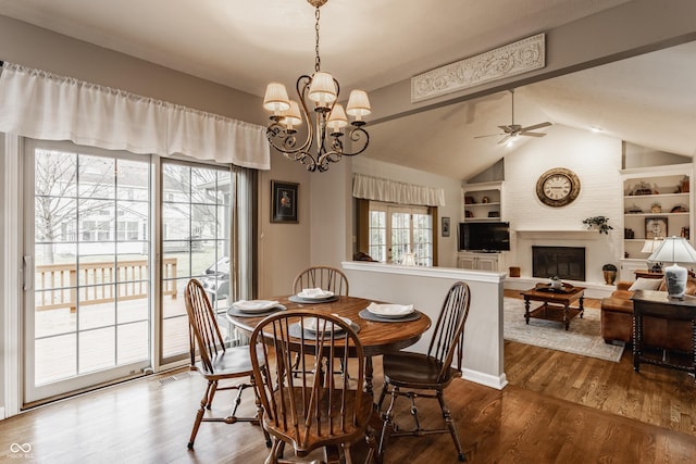 dining space with lofted ceiling, ceiling fan, wood finished floors, built in shelves, and a fireplace