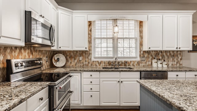 kitchen featuring tasteful backsplash, light stone countertops, stainless steel appliances, white cabinetry, and a sink