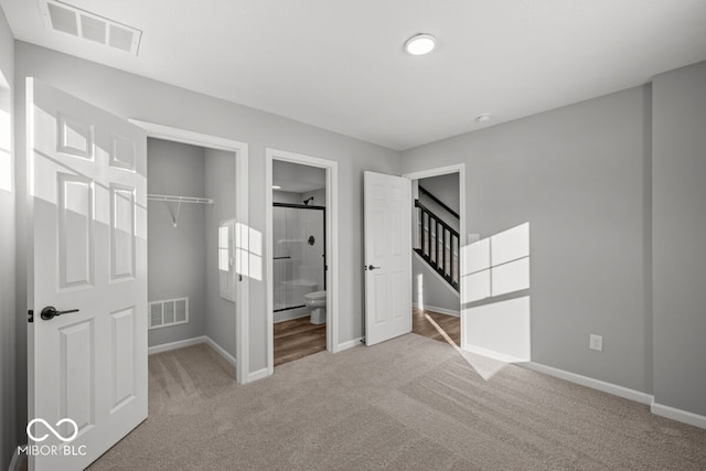 unfurnished bedroom with carpet floors, a walk in closet, a closet, and visible vents