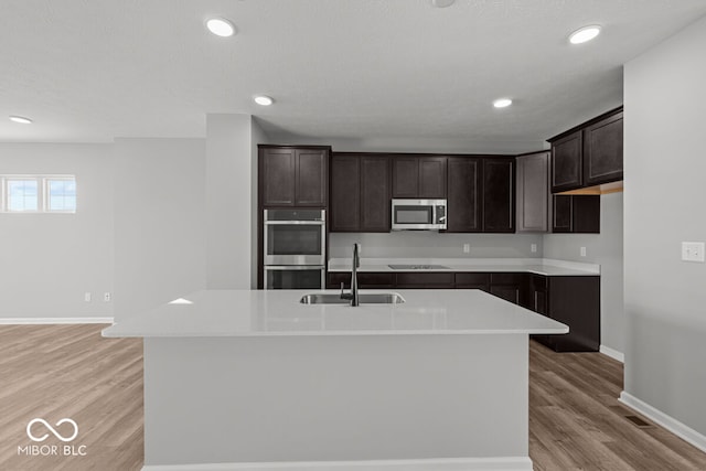 kitchen with light wood-style flooring, stainless steel appliances, a sink, and light countertops