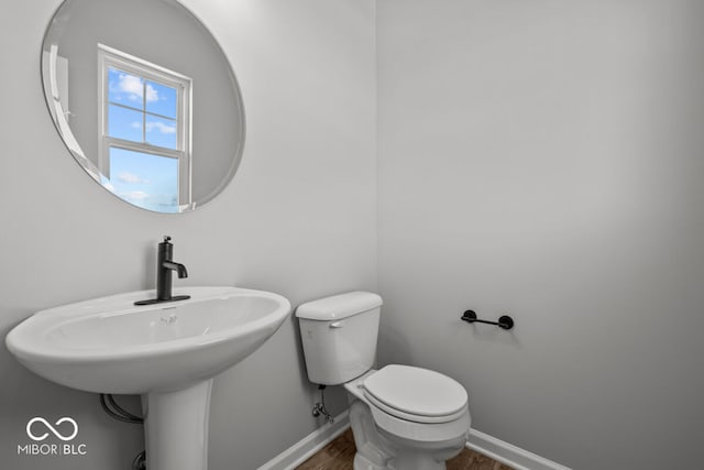 bathroom with wood finished floors, toilet, and baseboards