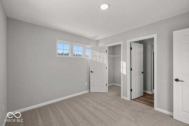 unfurnished bedroom with carpet, visible vents, a spacious closet, and baseboards