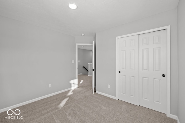 unfurnished bedroom with a closet, carpet flooring, and baseboards