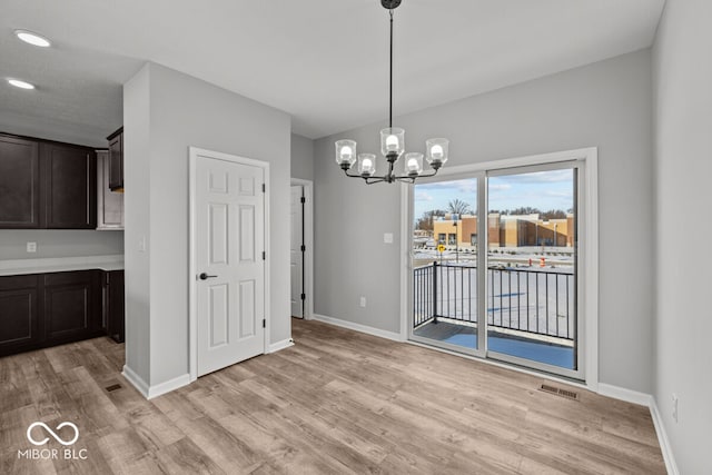 unfurnished dining area featuring a chandelier, visible vents, light wood-style flooring, and baseboards