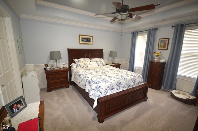 bedroom with light carpet, visible vents, a raised ceiling, a ceiling fan, and crown molding