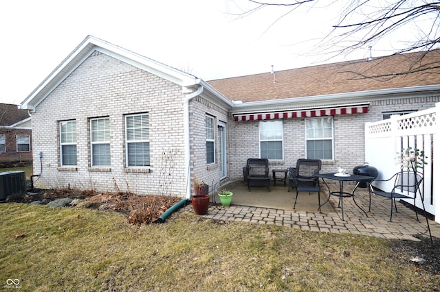 back of property with brick siding, a lawn, a patio area, and cooling unit